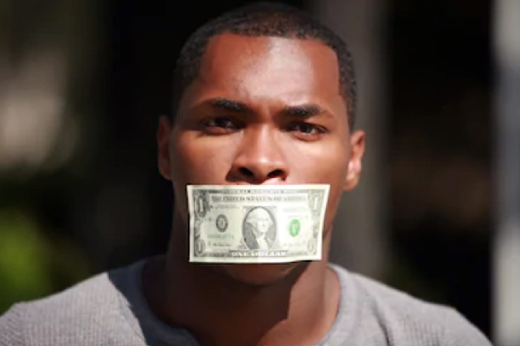 Man with money over mouth
