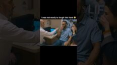 Man in a light-blue polo sits in a plane cabin, smiling as a clinician and another passenger laugh nearby.