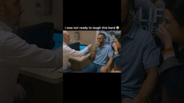 Man in a light-blue polo sits in a plane cabin, smiling as a clinician and another passenger laugh nearby.